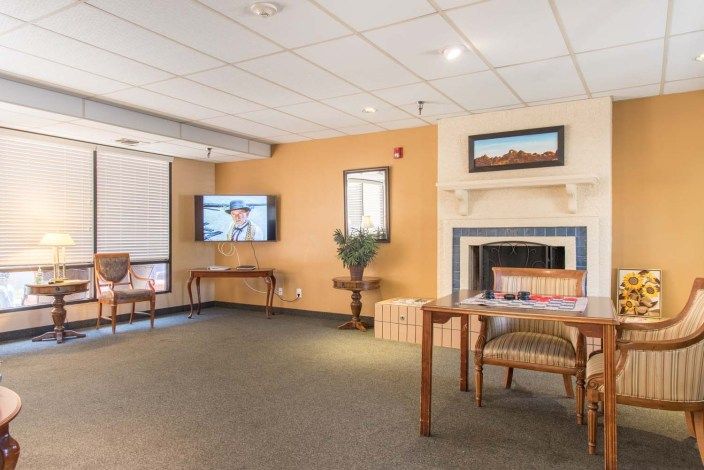 A cozy living room with a television mounted on the wall, a fireplace, and comfortable seating.