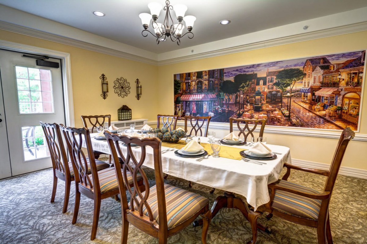 A beautifully decorated dining room with a large table and elegant chairs, featuring a chandelier and wall artwork.