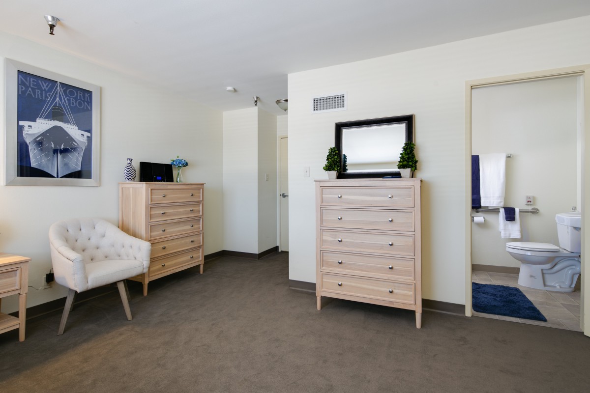Minimalist bedroom with neutral tones, featuring a pair of wooden chests of drawers and a mirror.