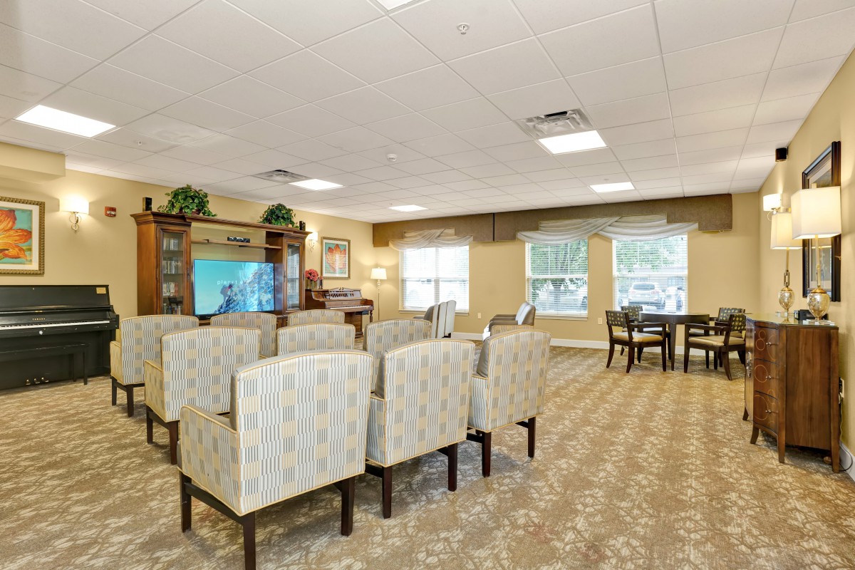 A well-arranged living room featuring multiple chairs, a television, and large windows that let in natural light.