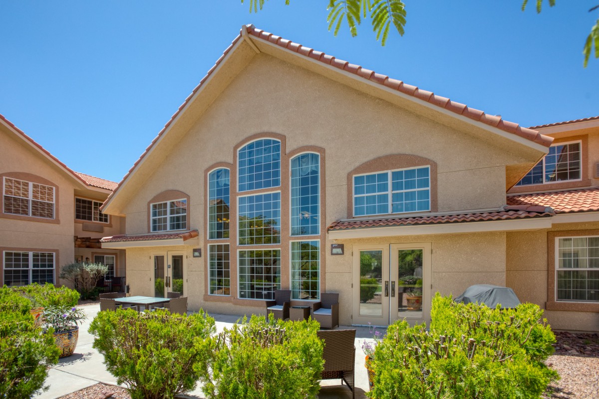 A beautiful house with large windows and a well-maintained patio area on a sunny day.