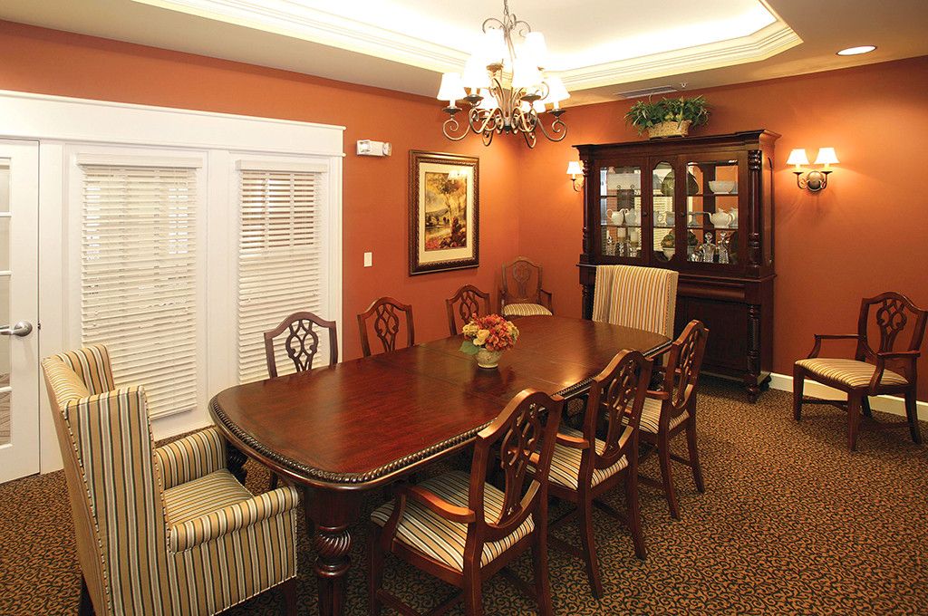 A formal dining room featuring a wooden table with matching chairs, a chandelier, and a china cabinet against warmly colored walls.