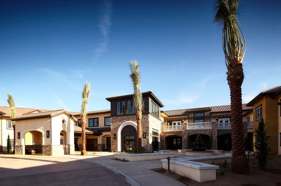 A modern building with palm trees in a sunny courtyard setting.