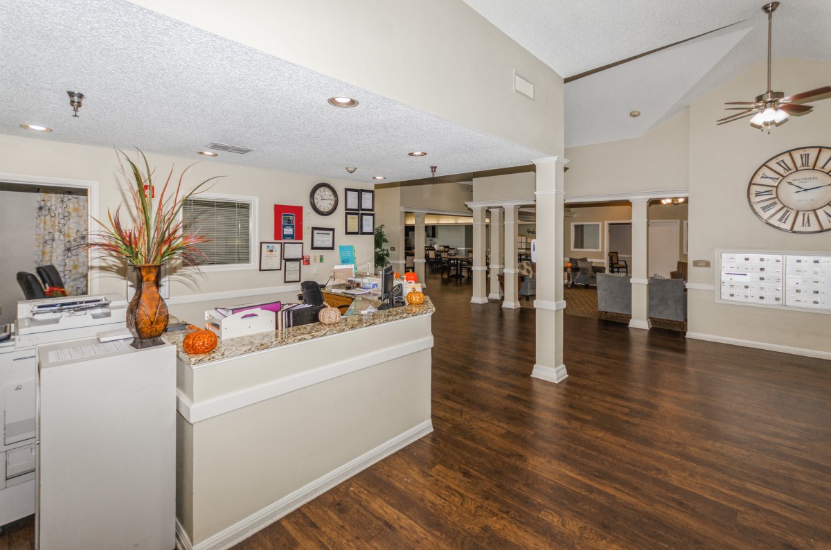 A modern reception area with a wooden floor, decorated desk, and open space design.