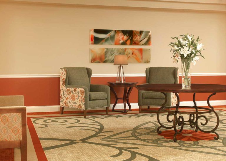 A lobby area with comfortable chairs, a decorative table, and artwork on the wall.