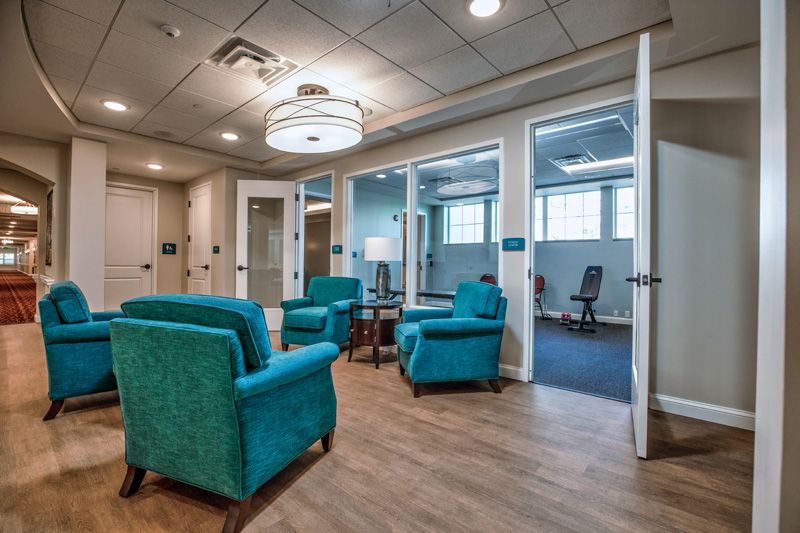 A modern waiting area featuring teal chairs and a bright, comfortable atmosphere.