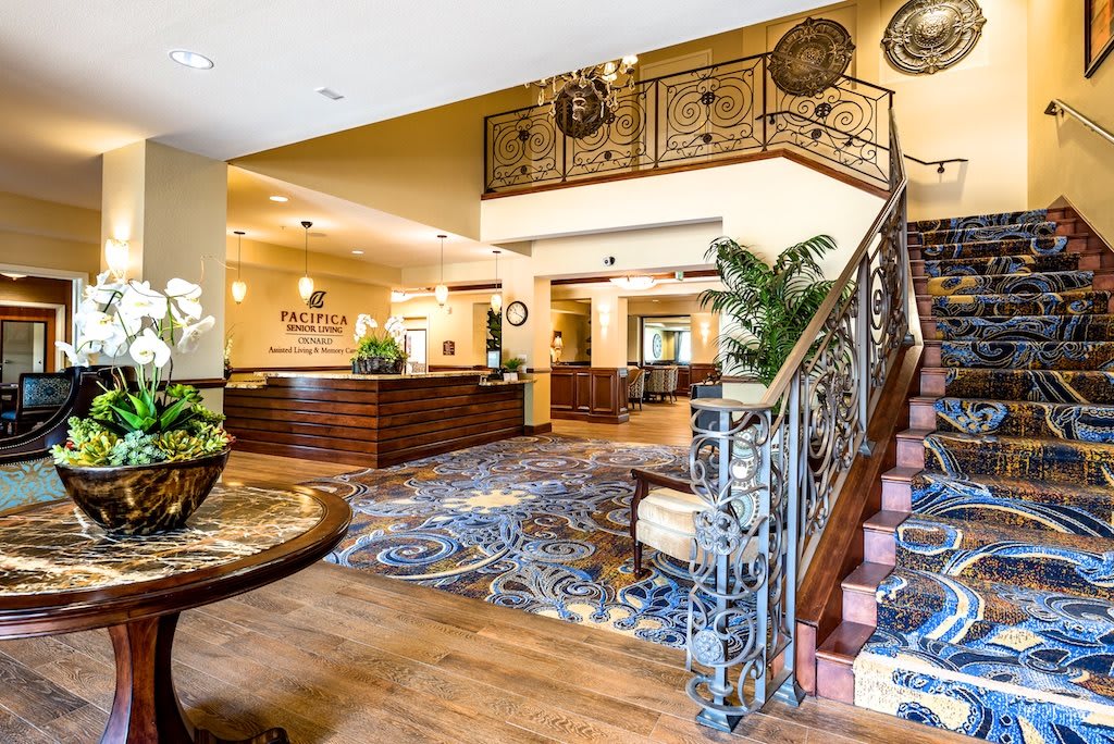 A hotel lobby featuring a reception desk and an ornate staircase.