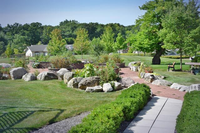 A serene garden landscape with a pathway surrounded by lush greenery and rocks.