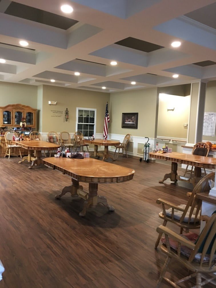 A spacious meeting room with wooden tables and chairs, decorated with an American flag and various items.