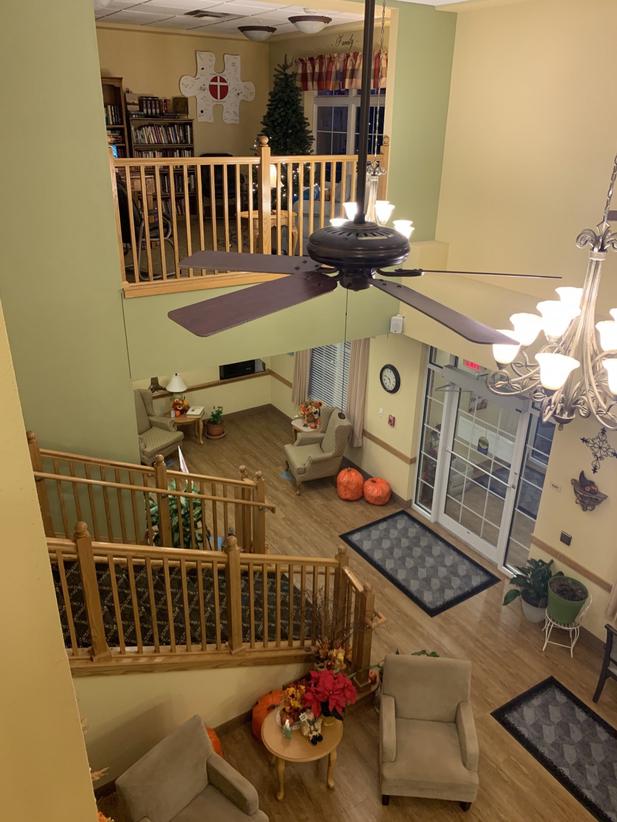 A spacious open-plan living area with a ceiling fan, staircase, and cozy seating.