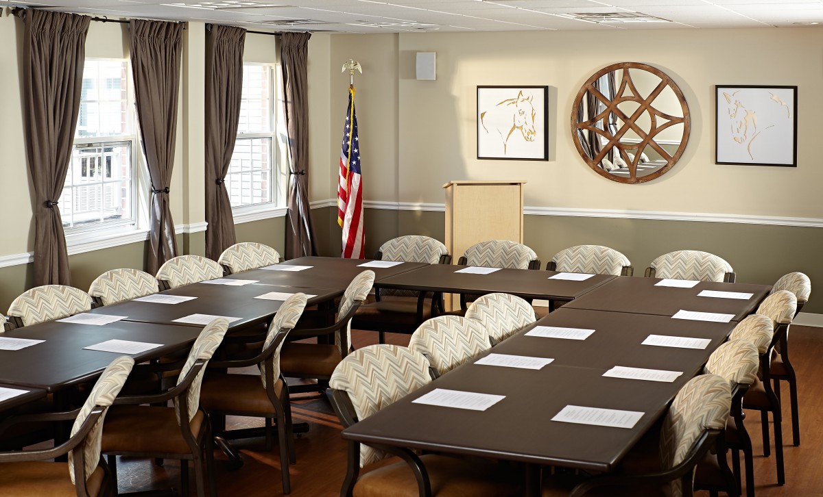 A well-organized conference room with tables, chairs, and a podium, featuring an American flag and decor elements.