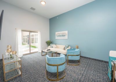 A modern living room with blue walls, featuring a sofa and stylish chairs.