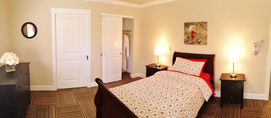 A cozy bedroom with a neatly made bed, nightstand, and closet.