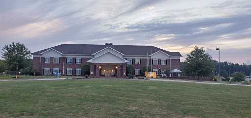 A welcoming residential building at dusk, featuring a broad lawn and an inviting entrance.