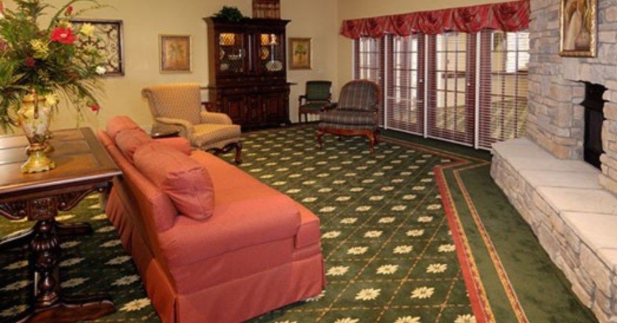 A cozy living room with a sofa, armchair, and patterned carpet.