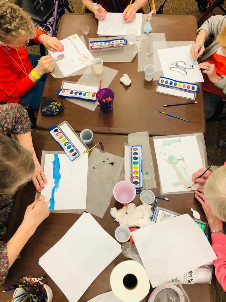 Children engaged in watercolor painting around a table.