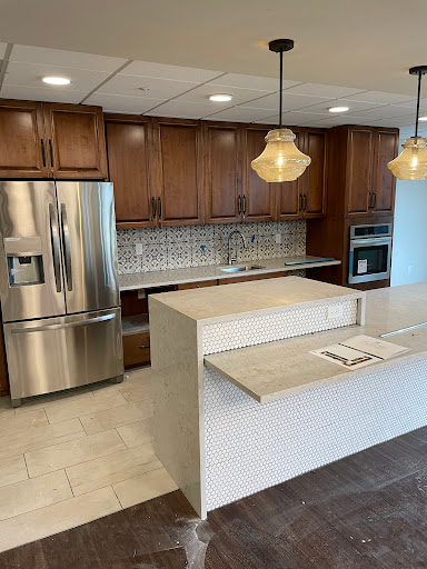 A modern kitchen featuring wooden cabinets, stainless steel appliances, and an elegant island with pendant lighting.