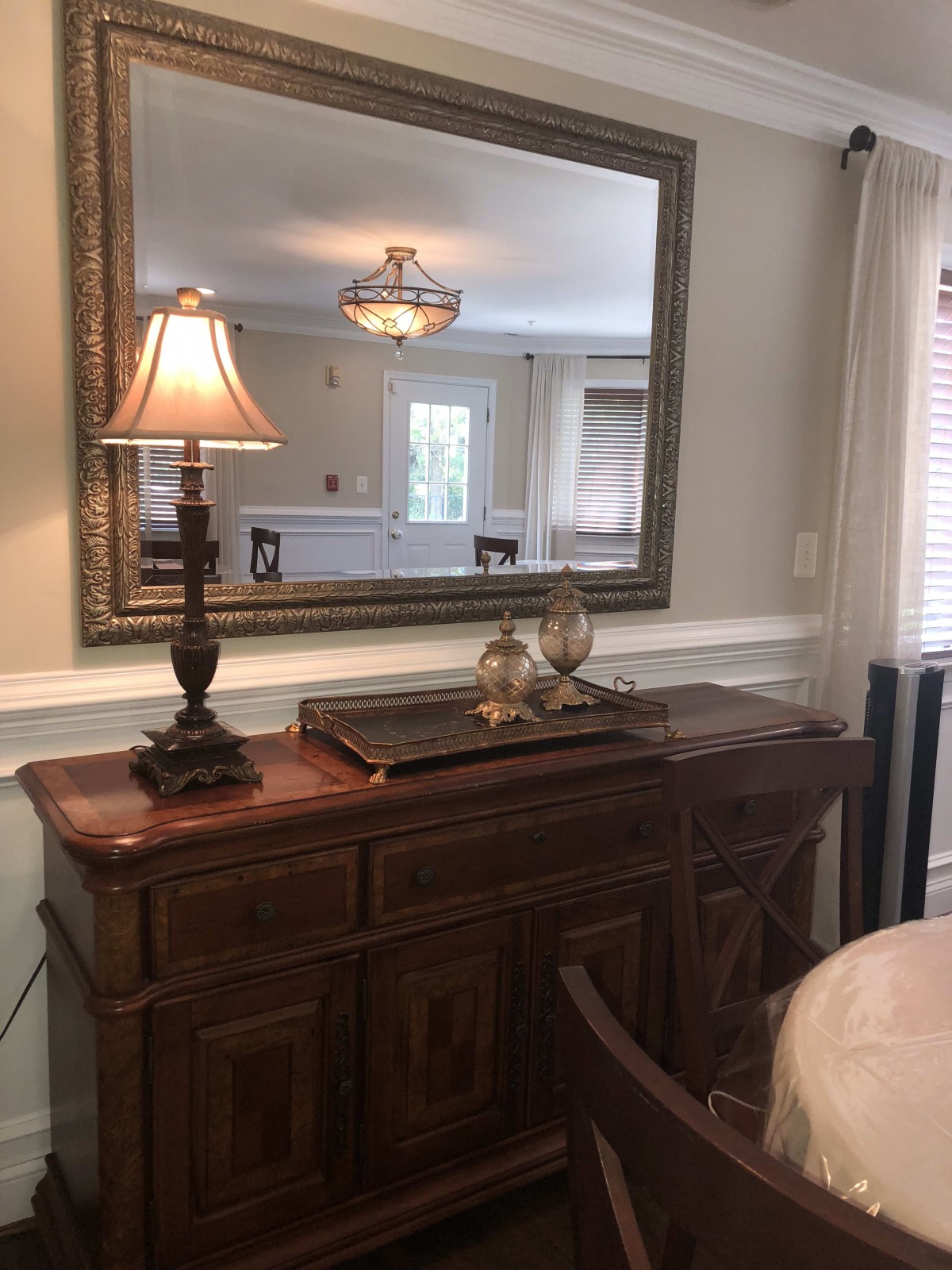 A classic interior setup featuring a wooden sideboard with a decorative lamp and mirror.