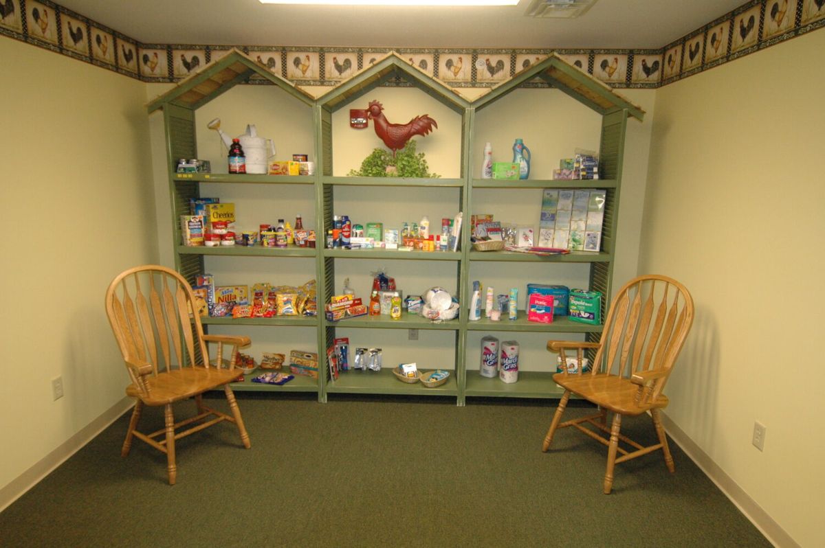 A cozy room with green shelves displaying various toys and items, flanked by two wooden chairs.
