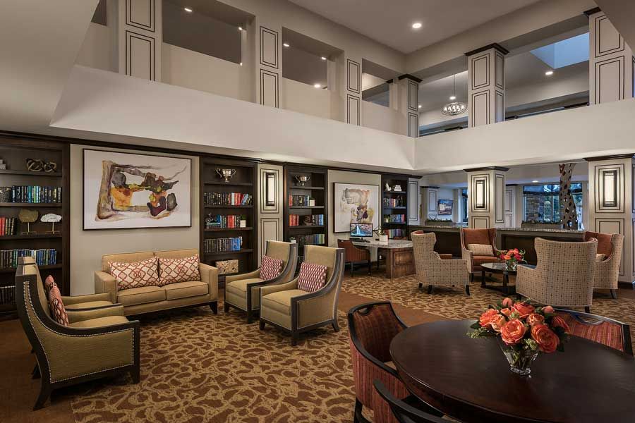 A cozy lobby area with comfortable seating, bookshelves, and artwork on the walls.