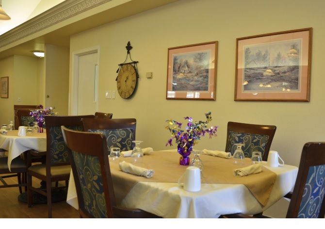 A neatly arranged dining room table with elegant decor and artwork on the walls.