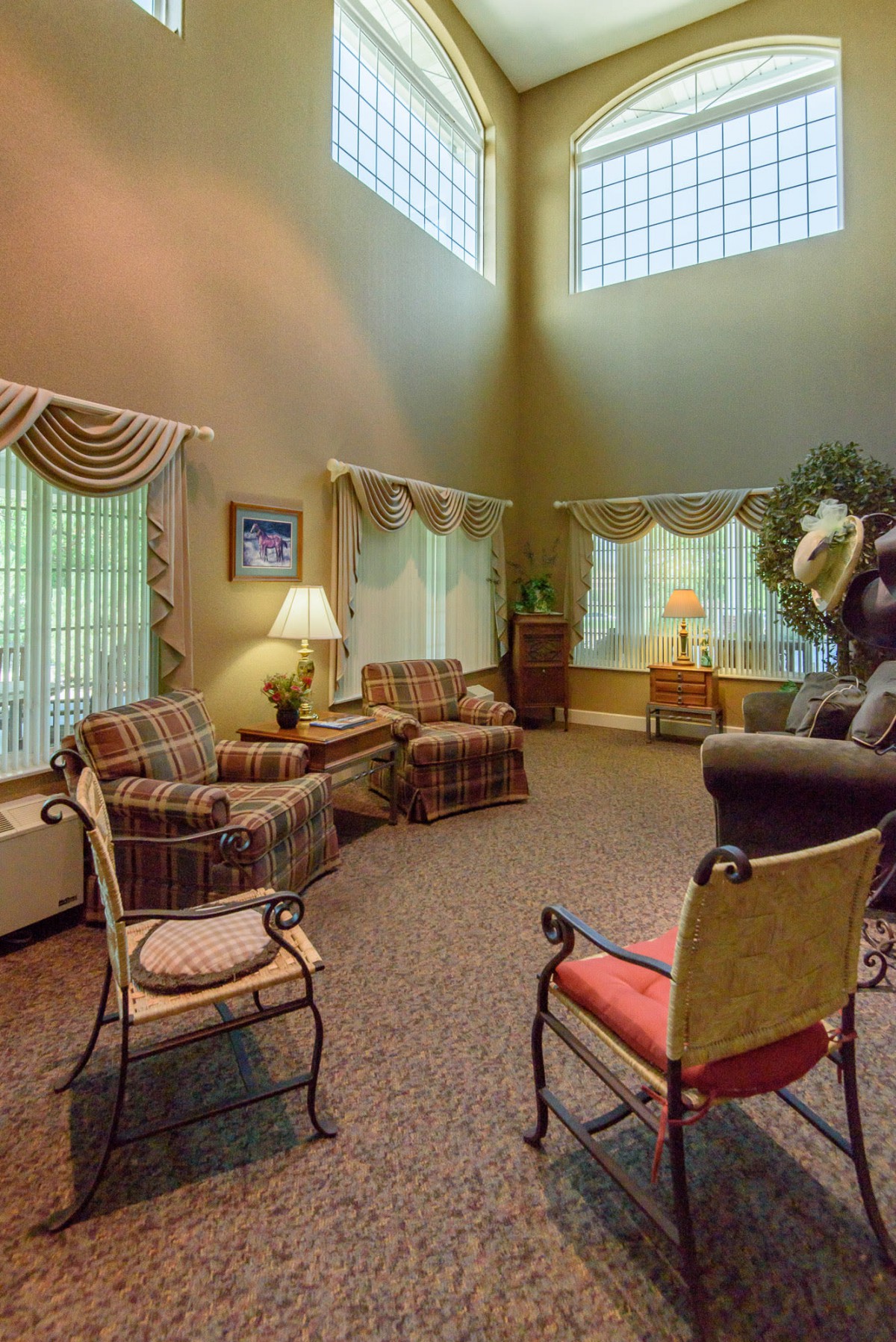 A spacious living room with comfortable seating, large windows, and elegant drapes.
