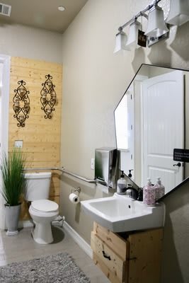 A well-decorated bathroom featuring a hexagonal mirror, a sink, and wall art.