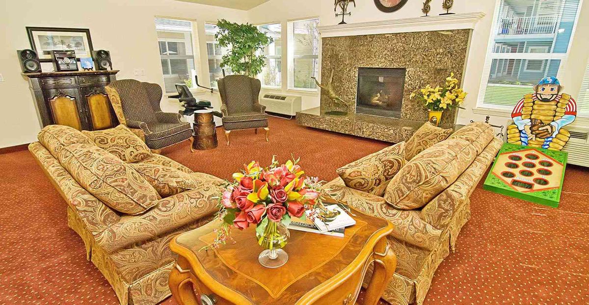 A cozy living room featuring comfortable sofas, a coffee table with a floral arrangement, and a fireplace.