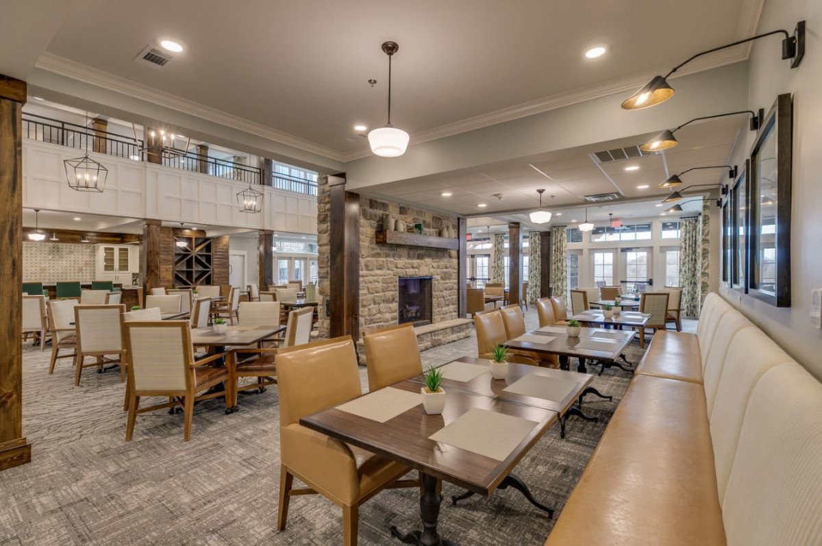 A modern restaurant dining area with elegant tables and chairs, featuring a central fireplace and ambient lighting.