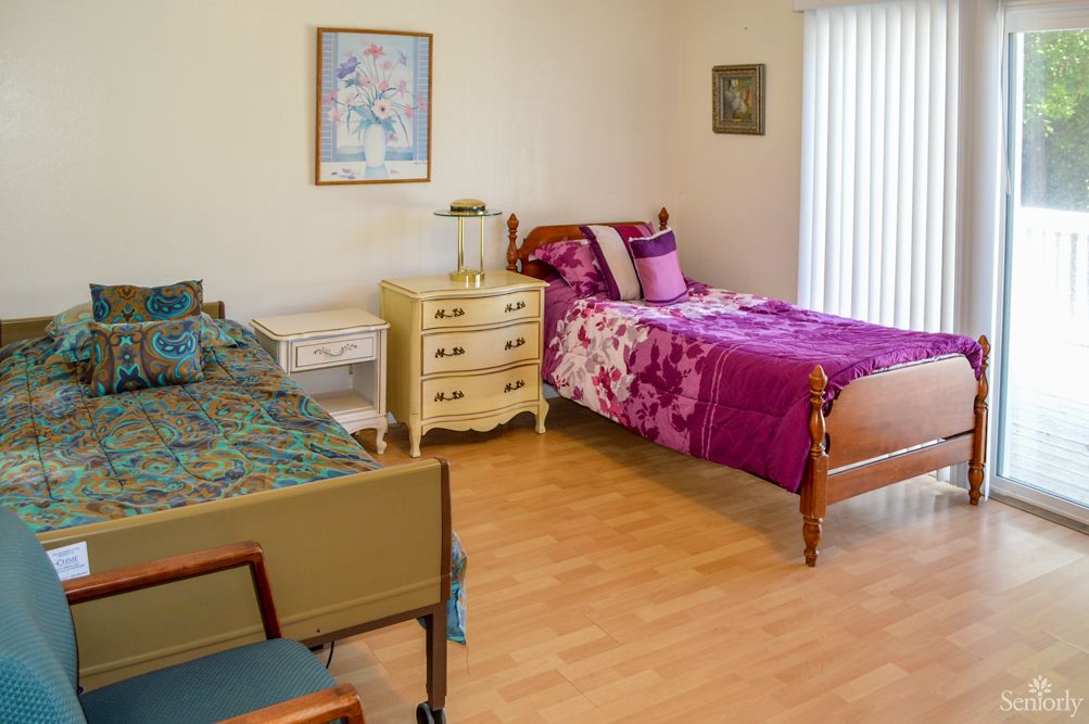 A cozy bedroom with two beds, featuring colorful bedding and wooden flooring.