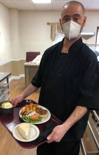 A chef serving a delicious meal in a kitchen.