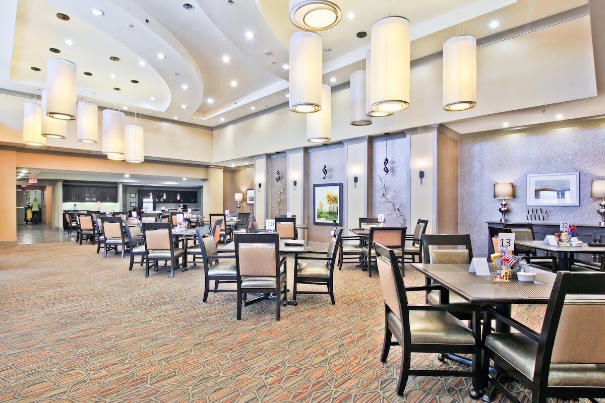 A spacious and elegantly decorated restaurant dining area with multiple tables and chairs.