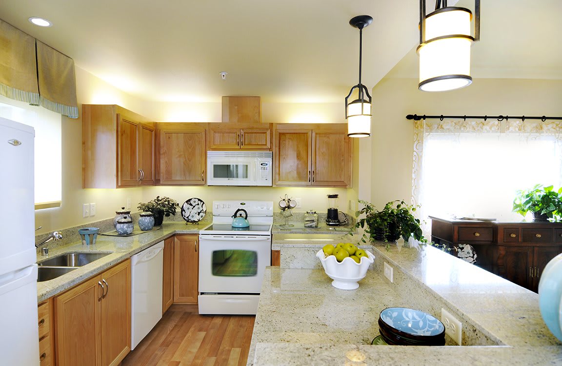 A modern kitchen with wooden cabinets, granite countertops, and sleek appliances.
