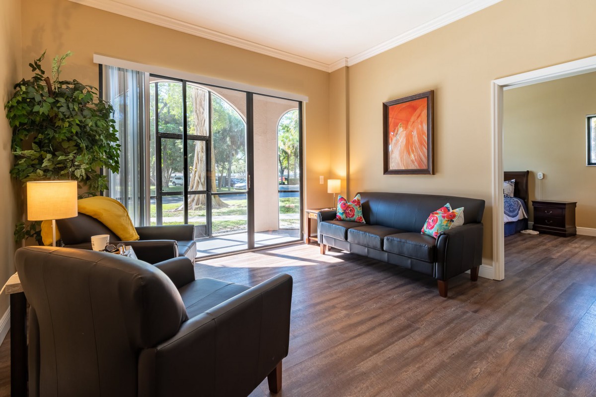 A cozy living room with modern furniture, large windows, and colorful artwork.