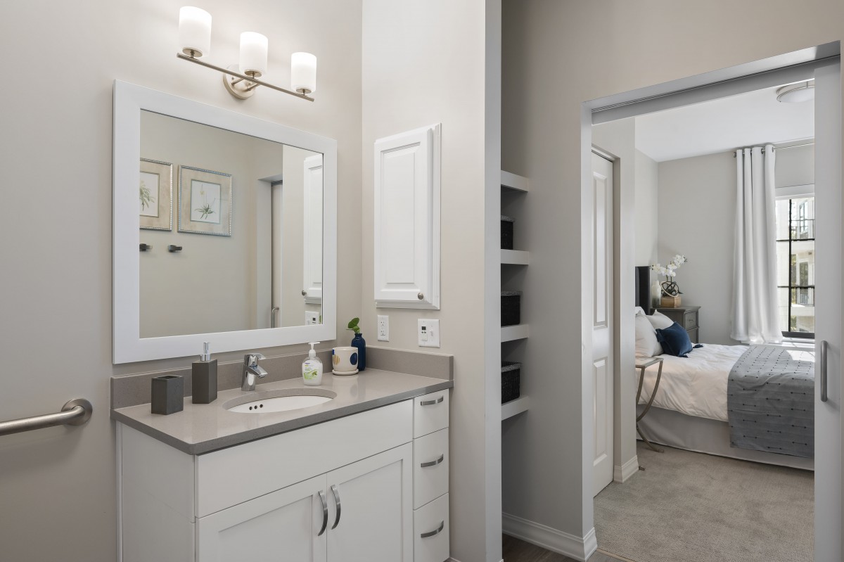 A modern bathroom featuring a white vanity with a large mirror and contemporary lighting.
