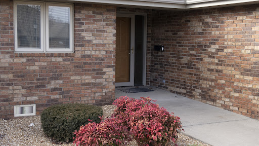 A welcoming entrance with brick walls and colorful plants.
