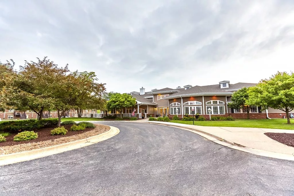 A large building with a circular driveway surrounded by trees and greenery under a cloudy sky.