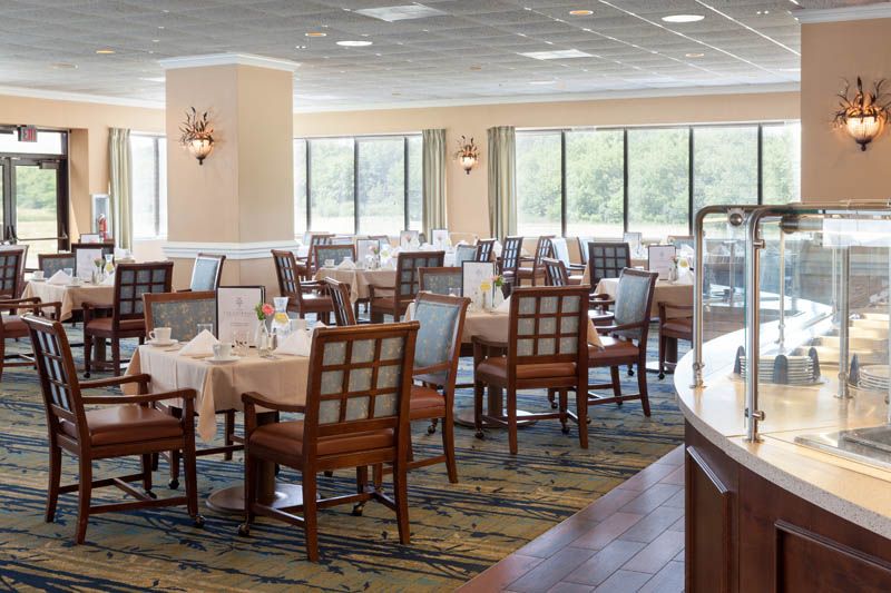 A spacious restaurant dining area with neatly arranged tables and chairs, surrounded by large windows.