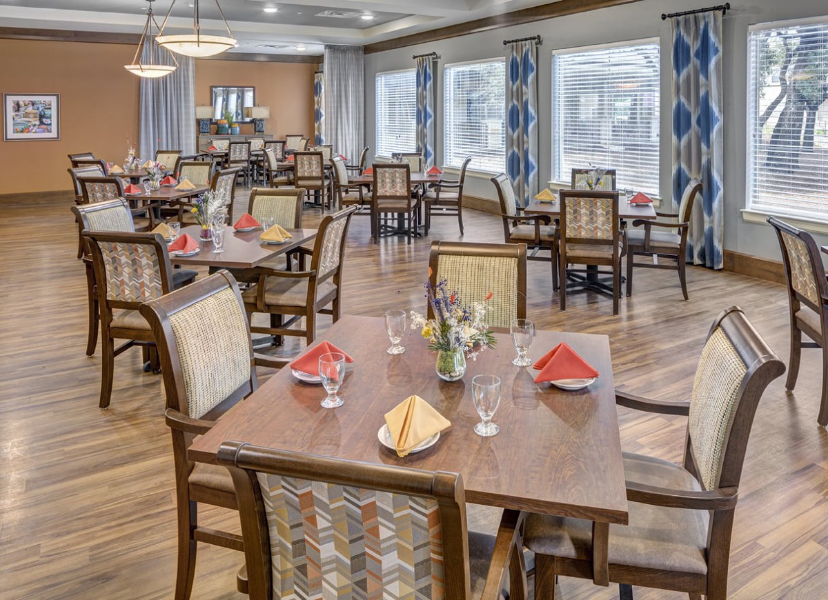 A well-arranged dining room with several tables and chairs, featuring elegant place settings.
