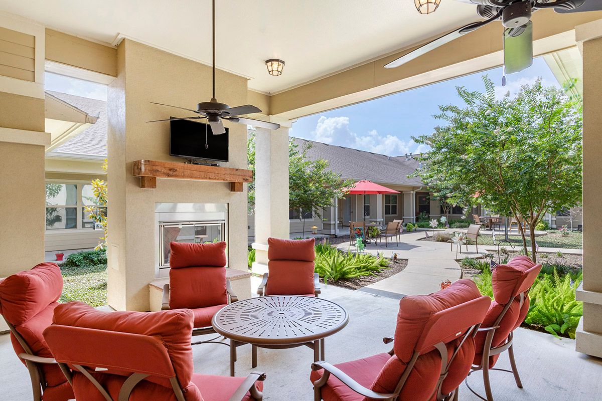 A cozy outdoor patio with red-cushioned seating, a table, and a garden view.