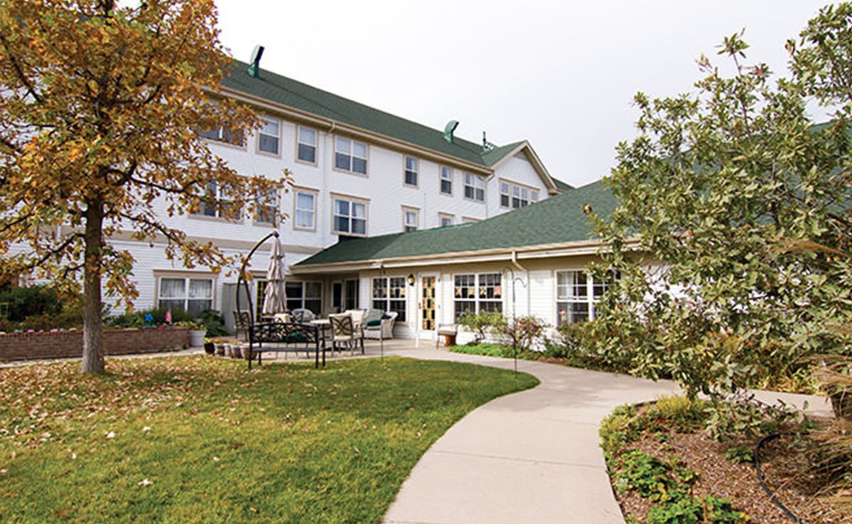 A well-maintained building with a green roof, surrounded by gardens and a walkway.