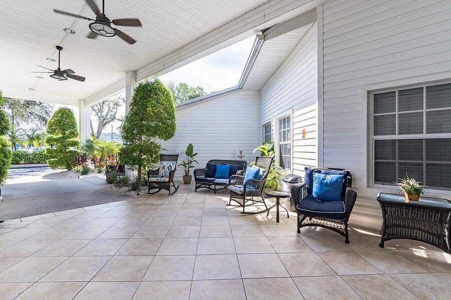 A spacious patio with comfortable seating, ceiling fans, and lush greenery.