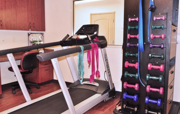 A home gym setup featuring a treadmill, dumbbells, and resistance bands.