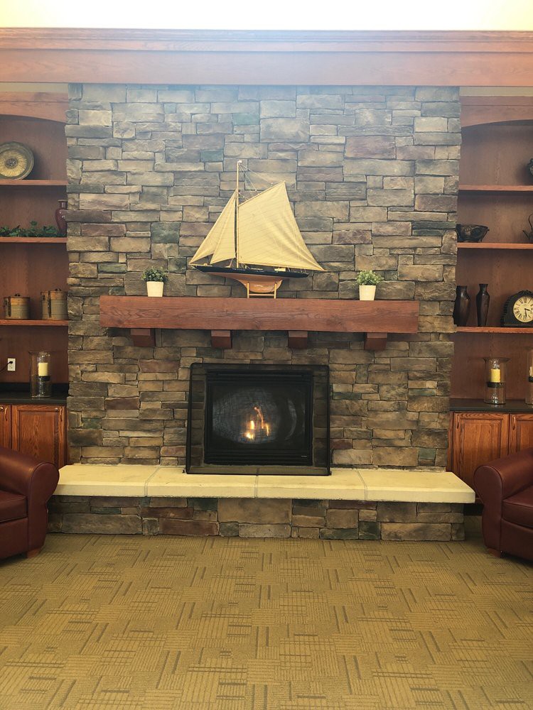 A cozy living room with a stone fireplace and sailboat decor.