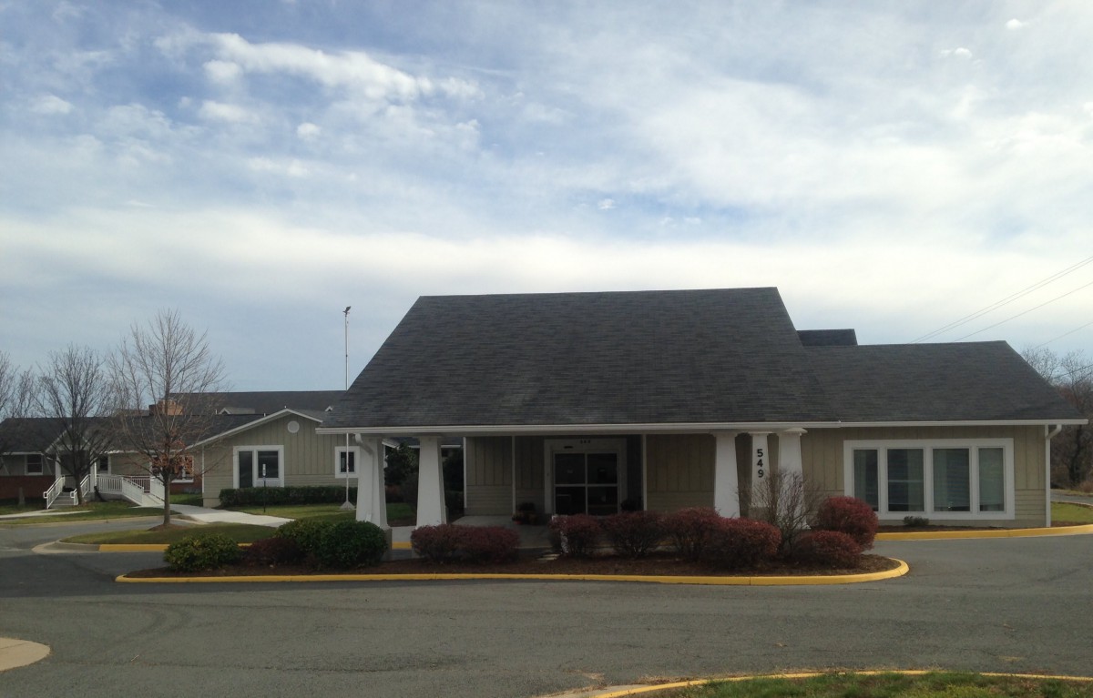 A suburban residential building with a sloped roof and landscaped surroundings.