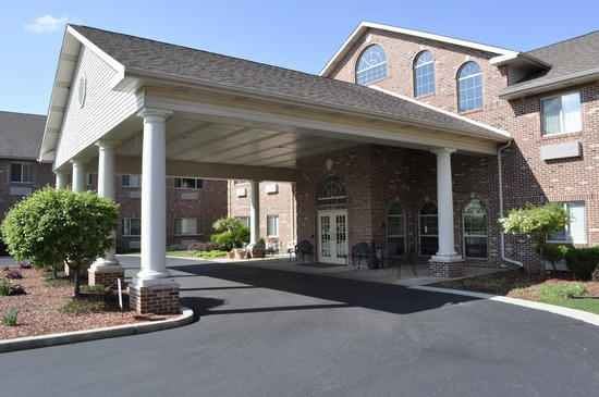 A brick building with a grand entrance featuring large white columns and an overhang.