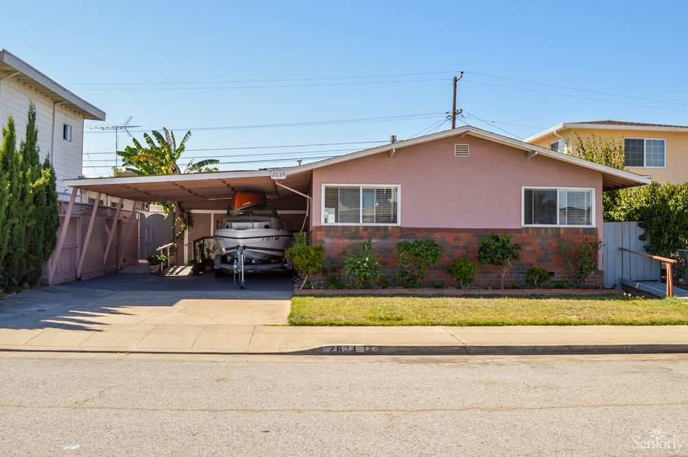 A single-story suburban house with a carport and a well-maintained front yard.