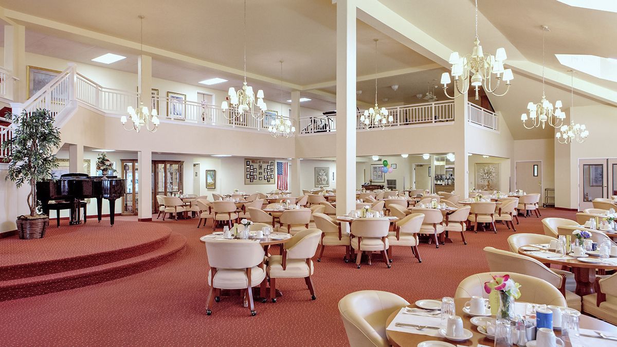 A spacious dining area with elegant chandeliers and arranged tables and chairs.