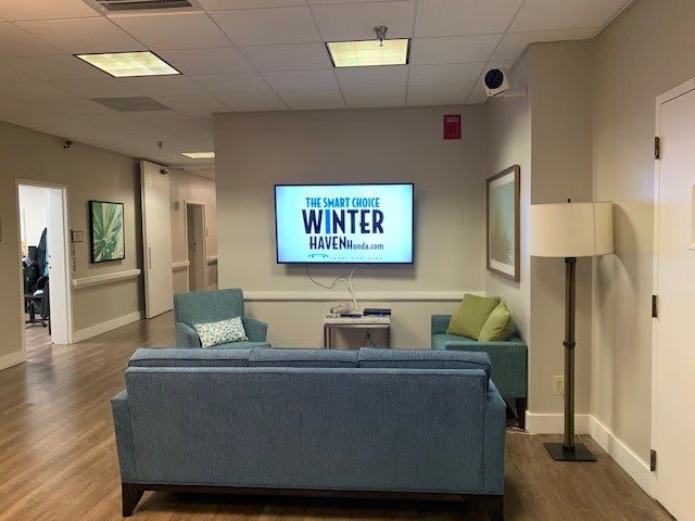 A cozy waiting room with sofas and a television displaying 'Winter Report' on the screen.