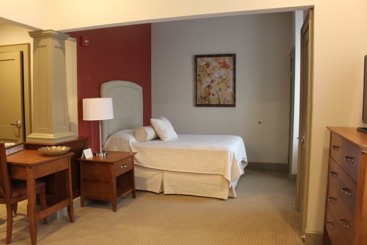 A cozy hotel room with a neatly made bed, nightstands, and ambient lighting.